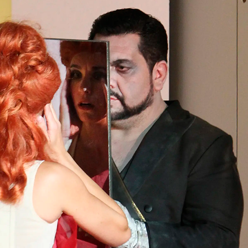 Luis gazing at his reflection through a mirror in a symbolic moment from Der Rosenkavalier.
